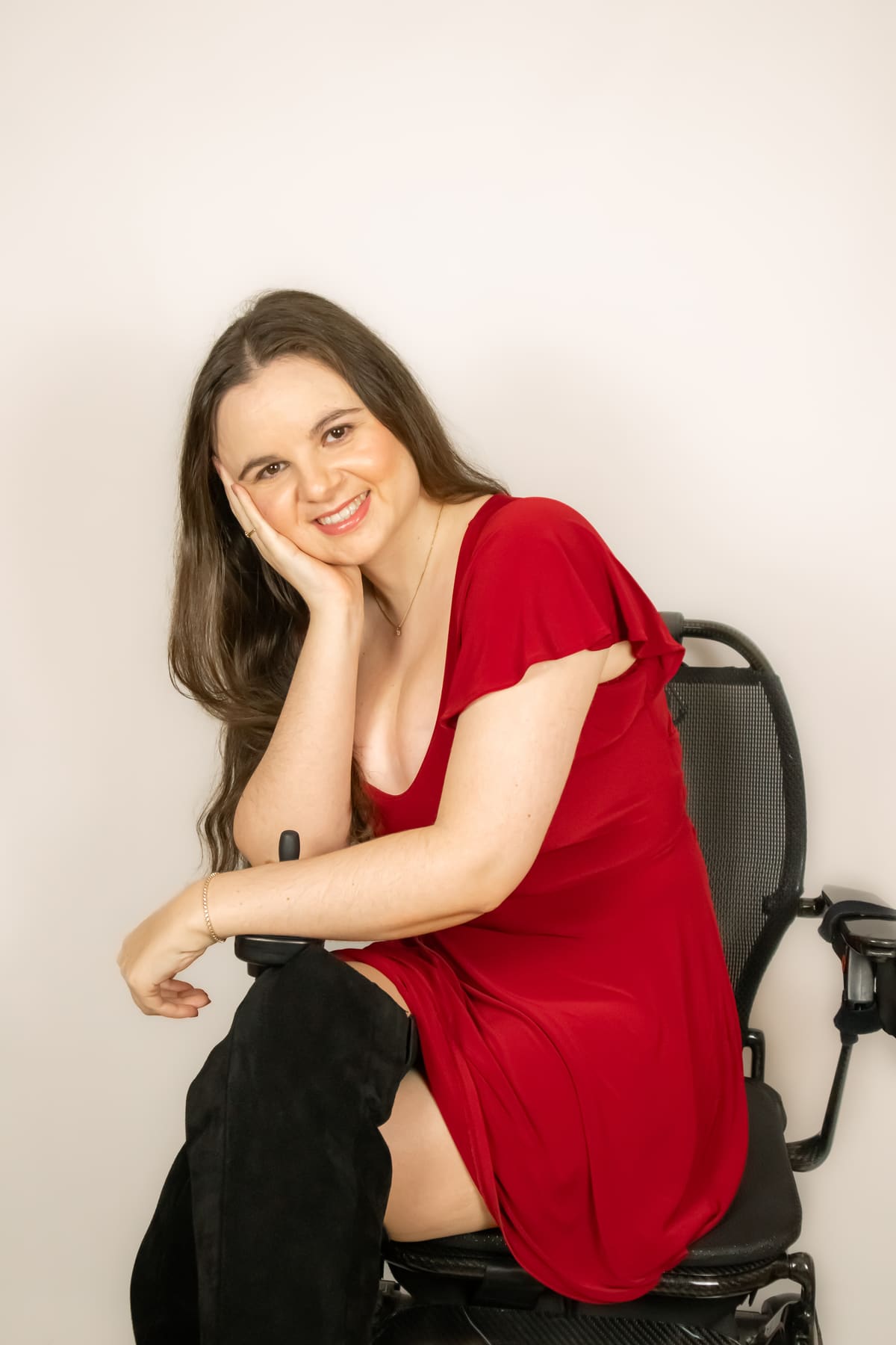 Rebeccah Prince, smiling warmly in a red dress, seated in her wheelchair.